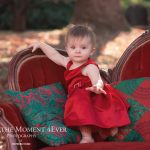baby girl in red dress holiday christmas photo session on victorian vintage style couch