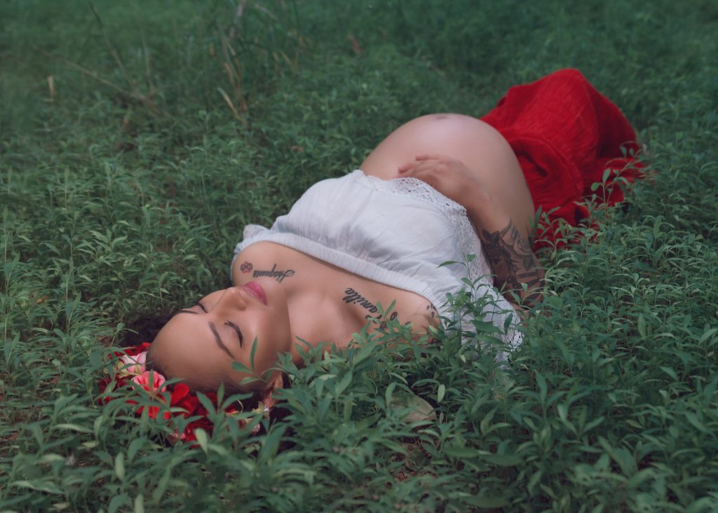 Mexican-themed Cultural Tribal Maternity dress shoot in Clarksville Tennessee TN red dress in the woods trees laying on the ground green grass