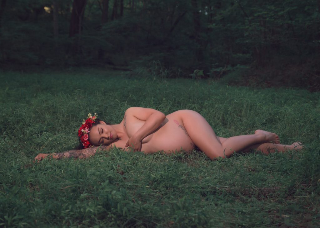 Mexican-themed Cultural Tribal Maternity dress shoot in Clarksville Tennessee TN red dress in the woods trees laying on the ground green grass nude