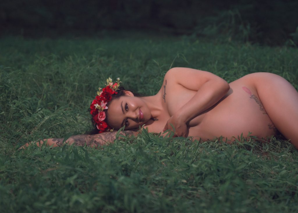 Mexican-themed Cultural Tribal Maternity dress shoot in Clarksville Tennessee TN red dress in the woods trees laying on the ground green grass nude