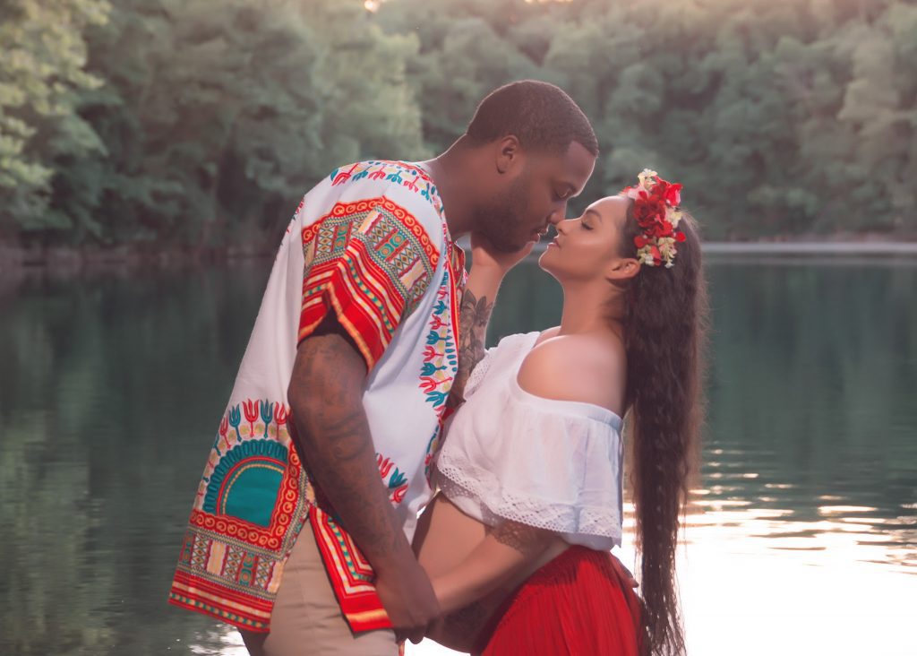 Mexican-themed Cultural Tribal Maternity dress shoot in Clarksville Tennessee TN red dress in the woods trees in the water at sunset couple husband and wife kissing