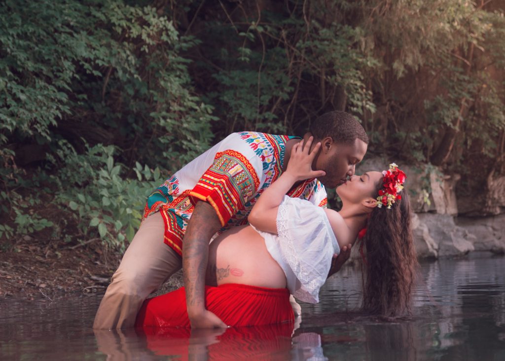 Mexican-themed Cultural Tribal Maternity dress shoot in Clarksville Tennessee TN red dress in the woods trees in the water at sunset couple husband and wife dip leaning back