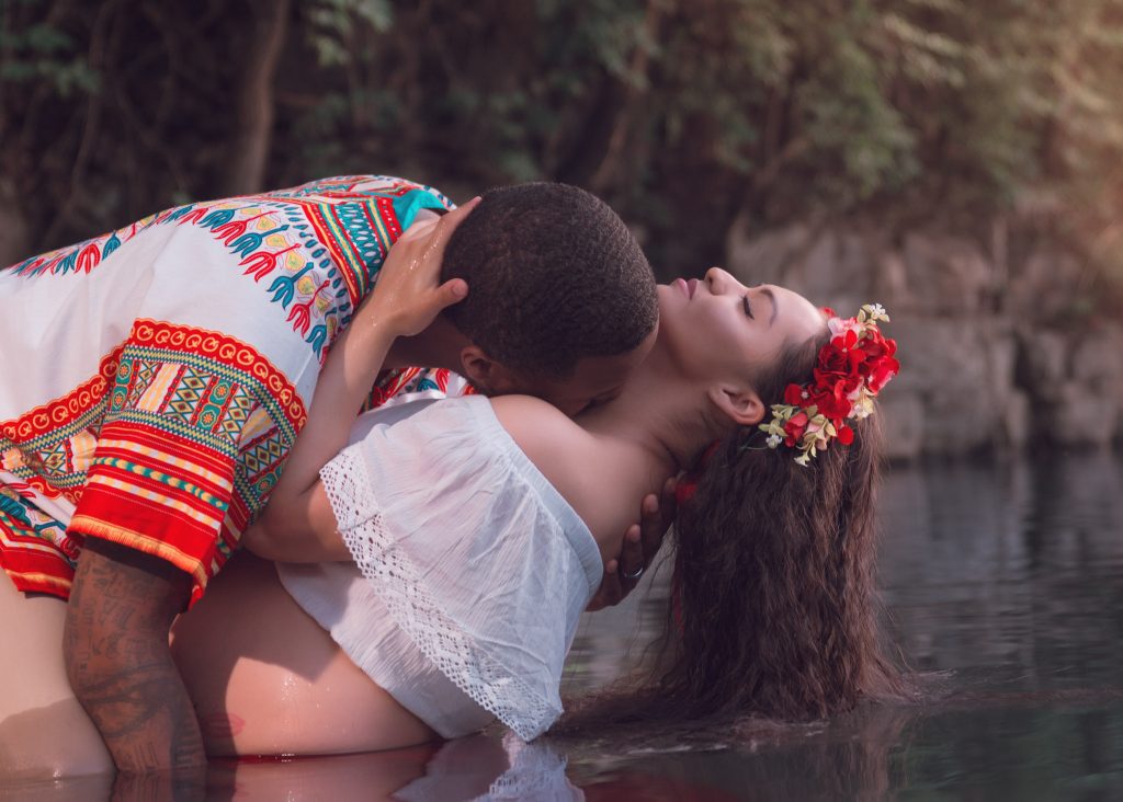 Mexican-themed Cultural Tribal Maternity dress shoot in Clarksville Tennessee TN red dress in the woods trees in the water at sunset couple husband and wife dip leaning back romantic kissing