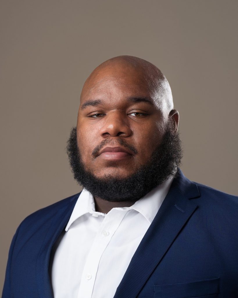 Black male business portrait on savage seamless backdrop with white shirt and blue suit