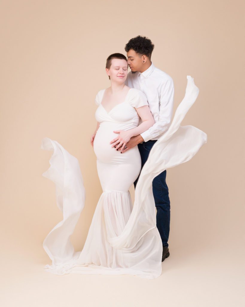 White maternity dress with toss in studio and husband