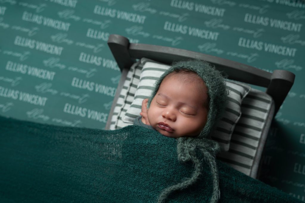 Newborn baby sleeping with green swaddle blanket