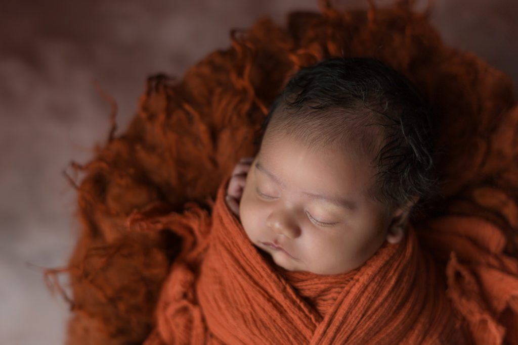 Newborn baby wrapped in orange sleeping