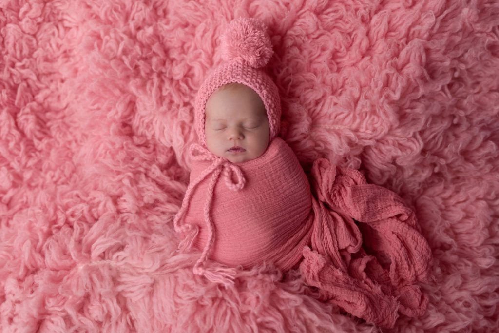 Newborn baby girl wrapped in pink sleeping