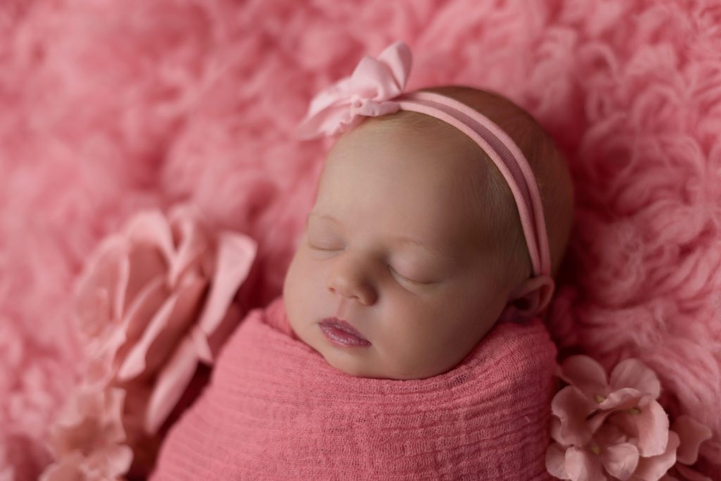 Newborn baby girl wrapped in pink sleeping