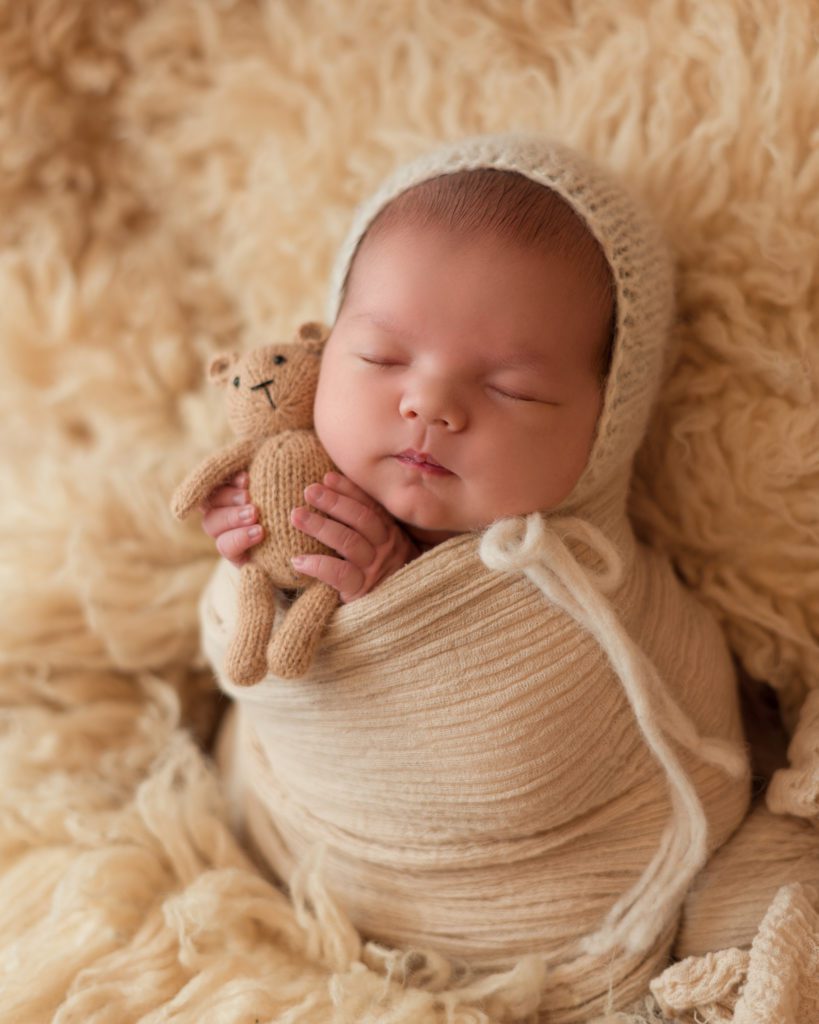 Newborn baby boy wrapped up with tan teddy bear