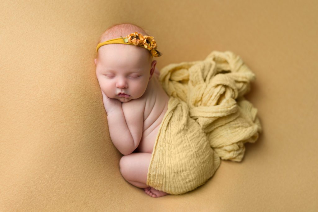 Newborn baby girl with yellow sunflowers sleeping