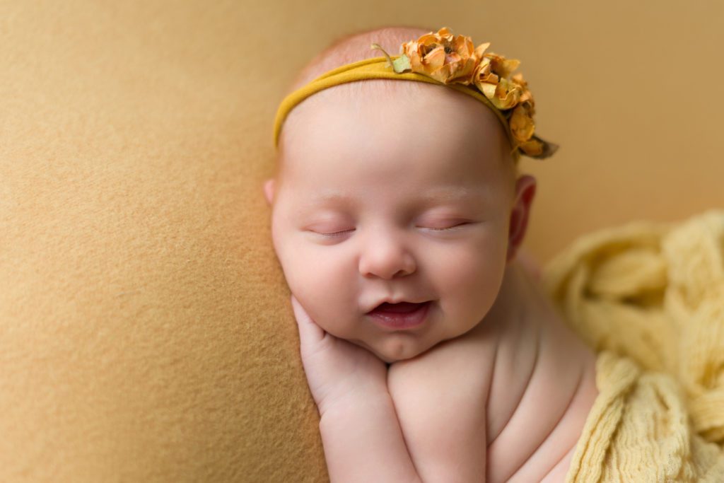 Newborn baby girl smiling with yellow sunflowers